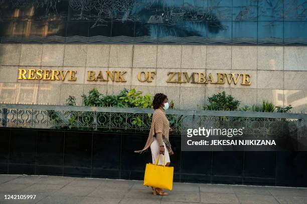 Woman walks outside the Zimbabwe Reserve Bank after its governor launched the country's new "Mosi-oa-Tunya" gold coin in Harare on July 25, 2022. The...