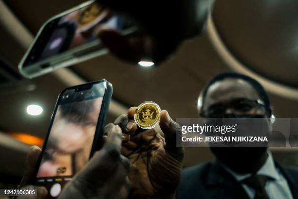 Zimbabwe Reserve Bank member of staff displays the country's new "Mosi-oa-Tunya" gold coin in Harare on July 25, 2022. - The new coin which weighs...