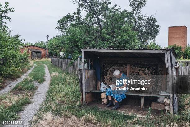 Tatiana, an 86-year-old woman, reads a book on a street in Soledar, Donetsk Oblast, Ukraine on July 25, 2022.