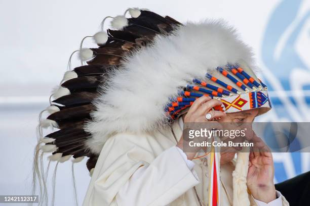 Pope Francis wears a traditional headdress that was gifted to him following his apology during his visit to Maskwacis, Canada on July 25, 2022. The...