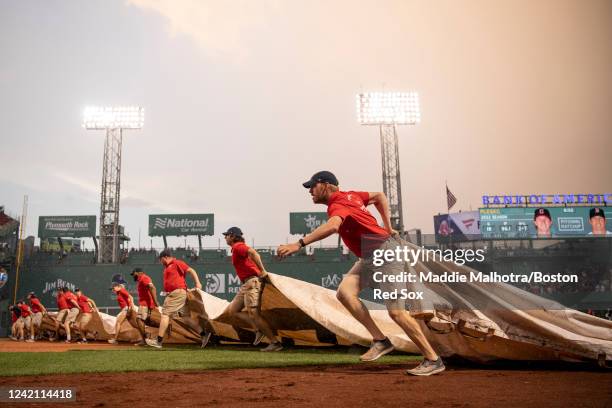 The Fenway Park Grounds Crew pulls the tarp over the infield during a game between the Boston Red Sox and the Cleveland Guardians on July 25, 2022 at...