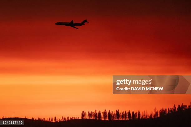 This photograph taken on July 25 shows a firefighting jet air tanker flying through a smoky sunset sky during the Oak Fire near Mariposa, California,...