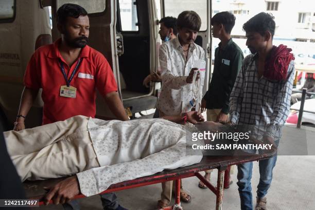 Man is shifted on a stretcher upon arriving in an ambulance at the Civil Hospital in Ahmedabad on July 26 after suffering health problems due to...