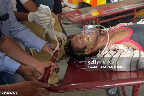 Man is shifted on a stretcher upon arriving in an ambulance at the civil hospital in Ahmedabad on July 26 after suffering health problems due to...