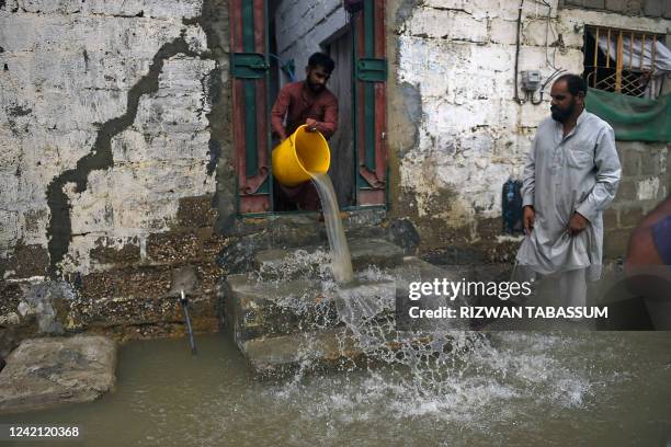 Resident uses a bucket to remove water from his flooded house after heavy monsoon rains in Karachi on July 26, 2022. A weather emergency was declared...