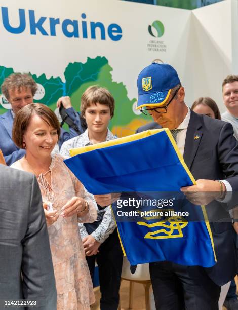 July 2022, Bavaria, Nuremberg: Federal Minister of Agriculture Cem Özdemir wears a Ukrainian cap, which he had received as a gift, and folds a...