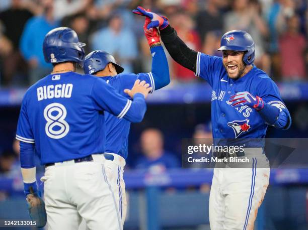 George Springer of the Toronto Blue Jays celebrates his grand slam with teammates Cavan Biggio and Santiago Espinal against the St. Louis Cardinals...