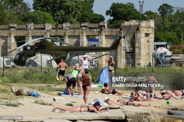 People relax on a beach of the Black Sea in Sevastopol, the largest city on the Crimean Peninsula and its most important port and naval base, with...
