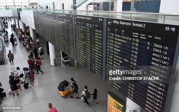 Passengers queue in front of counters and under a display announcing cancelled flights in the Lufthansa terminal at the Franz-Josef-Strauss Airport...