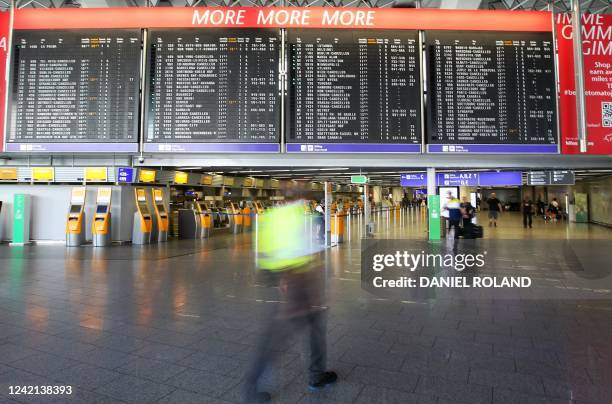 Display shows cancelled flights as passengers walk at Frankfurt Airport in Frankfurt am Main, western Germany, on July 27 after employees of German...