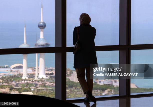 Woman stares at the Kuwait towers through a window from the al-Hamra Tower in Kuwait City, on July 27, 2022.