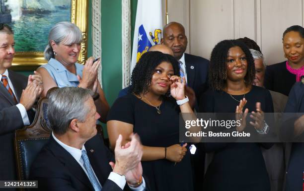 Deanna Cook, left, became emotional while speaking, after Governor Charlie Baker signed the CROWN Act at the Massachusetts State House. Her twin...