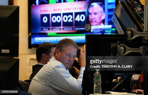 Person on the floor of the New York Stock Exchange watches TV screens on July 27, 2022. - US Federal Reserve on Wednesday again raised the benchmark...