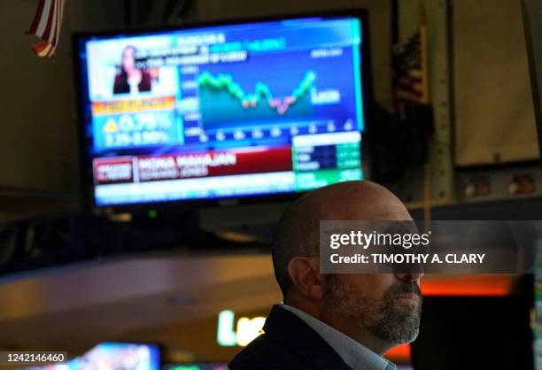 Person on the floor of the New York Stock Exchange watches TV screens on July 27, 2022. - US Federal Reserve on Wednesday again raised the benchmark...