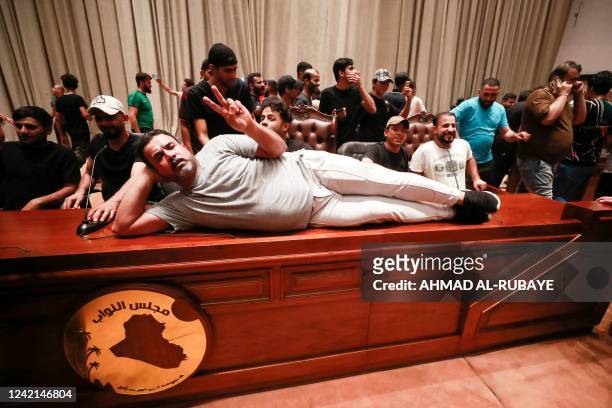 Supporter of the Iraqi cleric Moqtada Sadr, lies on the desk of the speaker of the Iraqi parliament, as demonstrators gather inside the Iraqi...
