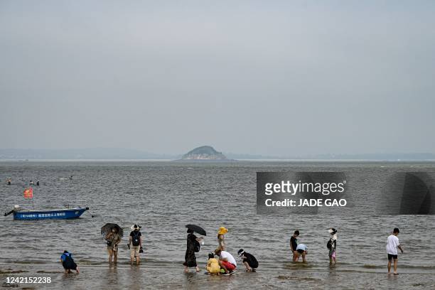 The photo taken on July 25, 2022 shows people relaxing on a beach where Taiwan's Jinmen Island can be seen at the back in Xiamen, in China's southern...