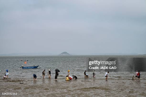 The photo taken on July 25, 2022 shows people relaxing on a beach where Taiwan's Jinmen Island can be seen at the back in Xiamen, in China's southern...