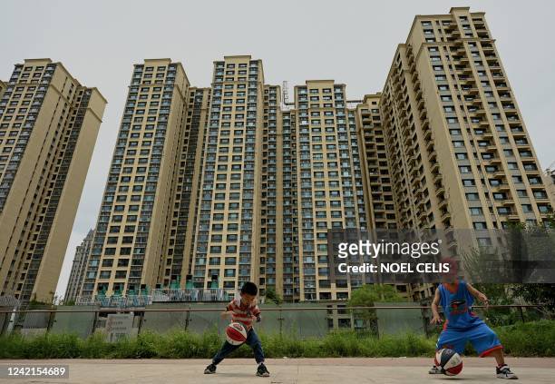 Children play basketball in front of a housing complex by Chinese property developer Evergrande in Beijing on July 28, 2022.