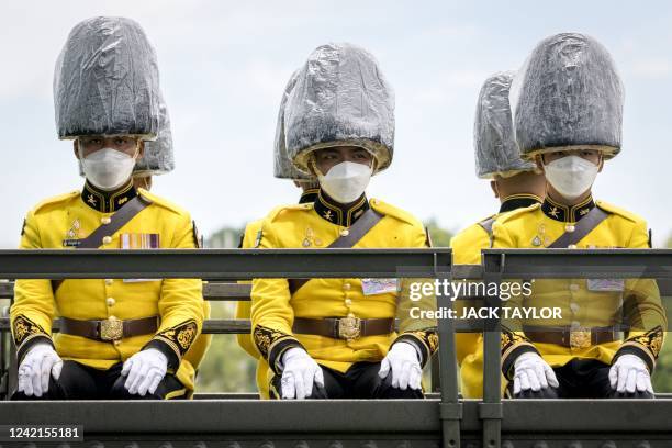 Members of the 1st field Artillery Regiment, King's Guard wear waterproof head coverings during celebrations in front of the Grand Palace for the...