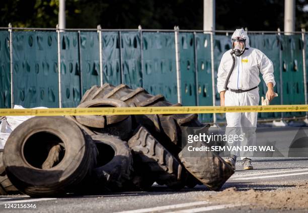 An employee of a contracting company cleans up asbestos on the A1 motorway in Voorst, eastern Netherlands on July 28, 2022. - The motorway is closed...