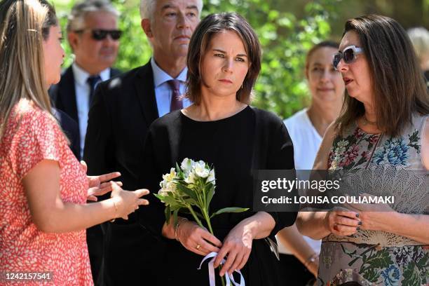 German Foreign Minister Annalena Baerbock holds flowers while listening to members of the Jewish community in Athens, during her visit to the...