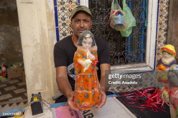 Worker pose for a photo with his prepared candy figure as part of Hijri New Year's events in Nabel, Tunisia on July 21, 2022. Candies made from...