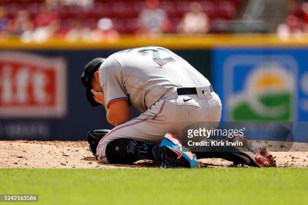 Daniel Castano of the Miami Marlins grabs his face after being hit by a line drive while pitching during the first inning of the game against the...