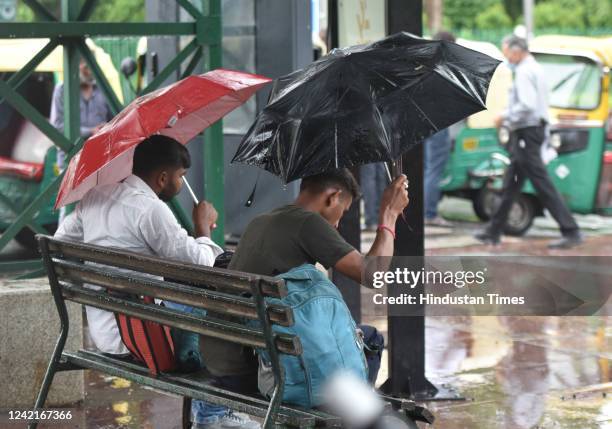 Two men with umbrella take rest on bench as it rains at Connaught Place on July 28, 2022 in New Delhi, India. Parts of the national capital region...