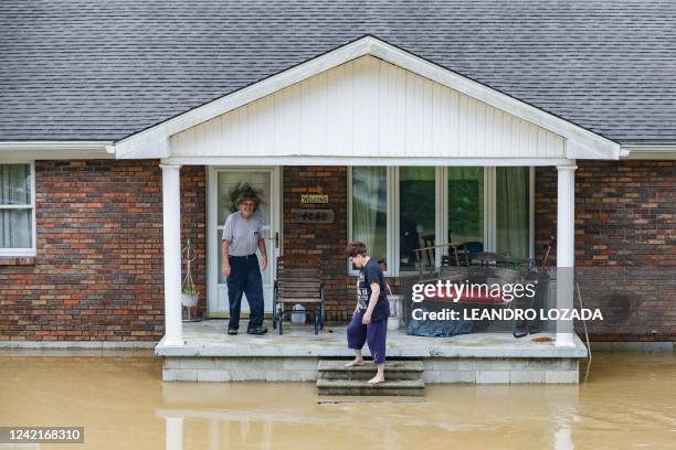 Couple stands on the porch of their home flooded by the waters of the North Fork of the Kentucky River in Jackson, Kentucky on July 28, 2022. - At...