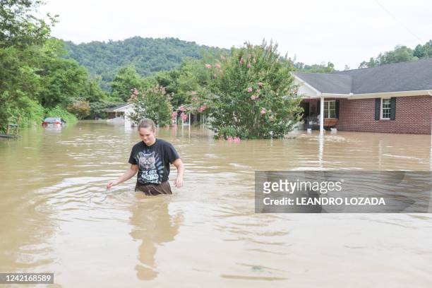 Young woman walks through waist-deep water next to a house flooded by the waters of the North Fork of the Kentucky River in Jackson, Kentucky on July...