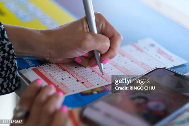 Woman checks off the numbers chosen for her Mega Millions lottery tickets at a 7-Eleven convenience store in Chino Hills, California on July 28,...