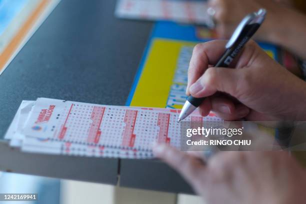 Woman checks off the numbers chosen for her Mega Millions lottery tickets at a 7-Eleven convenience store in Chino Hills, California on July 28,...