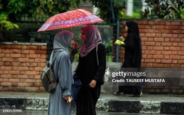 Burqa-clad women walk along a street amid the monsoon rains in Srinagar on July 29, 2022.