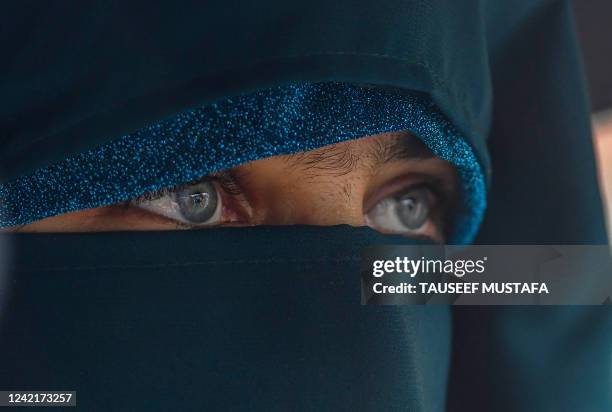 Burqa-clad woman walks along a street amid the monsoon rains in Srinagar on July 29, 2022.