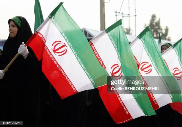 Female members of the Iranian Basij militia march past President Mahmoud Ahmadinejad as they hold their country's flag during the annual army day...