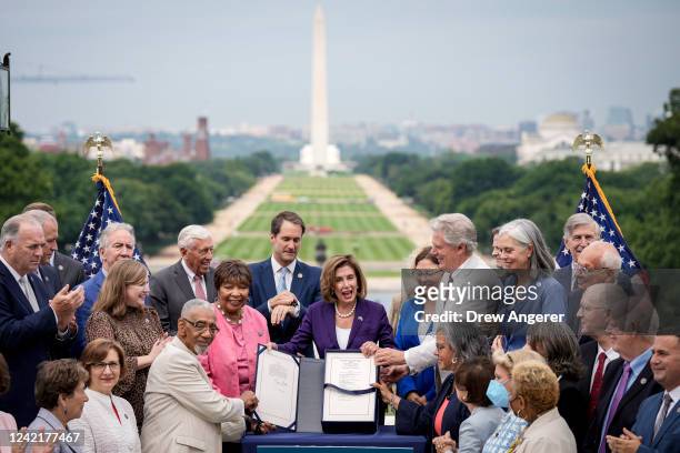 Surrounded by House Democrats, Speaker of the House Nancy Pelosi holds up the CHIPS For America Act during a bill enrollment ceremony outside the...
