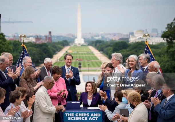 Surrounded by House Democrats, Speaker of the House Nancy Pelosi smiles after signing the CHIPS For America Act during a bill enrollment ceremony...
