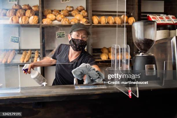 bakery owner wiping down surfaces wearing mask. - acrylic glass stock pictures, royalty-free photos & images