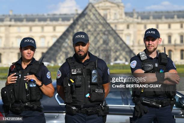 French police officers stand guard with the Louvre Museum in the background in Paris on July 29, 2022.