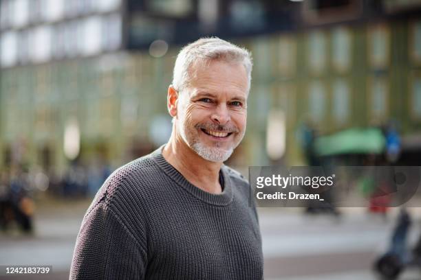 homem de cabelo grisalho maduro olhando para a câmera e sorrindo - cultura holandesa - fotografias e filmes do acervo