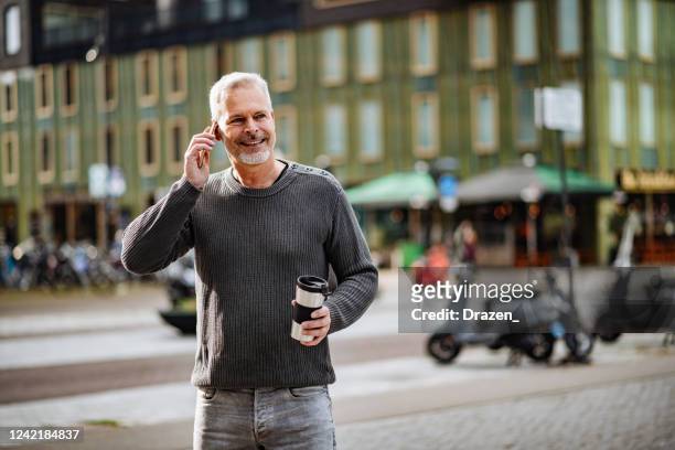 mature gray hair man using smart phone in the city during pandemic - amsterdam business stock pictures, royalty-free photos & images