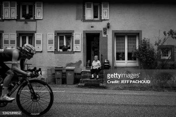 An elderly woman on her doorstep looks at a cyclist passing by during the 6th stage of the new edition of the Women's Tour de France cycling race 2...