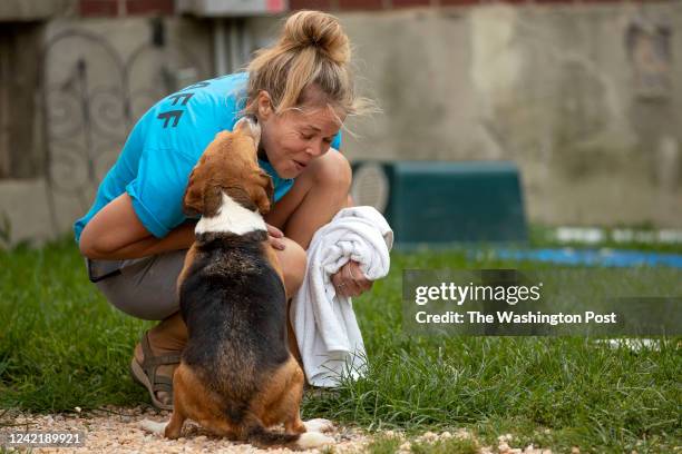 Sue Bell laughs as she is licked by a beagle at Homeward Trails Animal Rescue in Fairfax, Virginia on July 21, 2022.