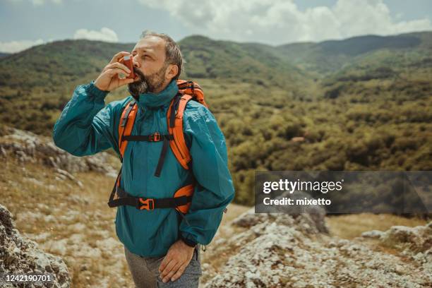 hombre maduro usando inhalador de asma - asmático fotografías e imágenes de stock