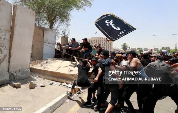 Supporters of the Iraqi cleric Moqtada Sadr bring down concrete barriers leading to the capital Baghdad's high-security Green Zone and the country's...