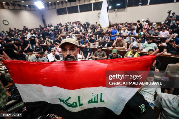 Man deploys a national flag as supporters of the Iraqi cleric Moqtada Sadr gather inside the country's parliament in the capital Baghdad's...