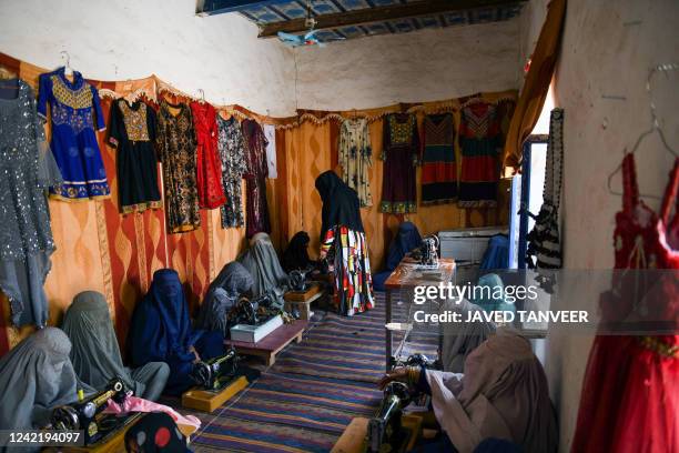 Afghan burqa-clad women use the sewing machine at a handicraft workplace in Kandahar on July 30, 2022.