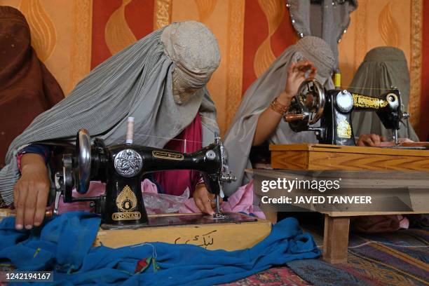 Afghan burqa-clad women use the sewing machine at a handicraft workplace in Kandahar on July 30, 2022.