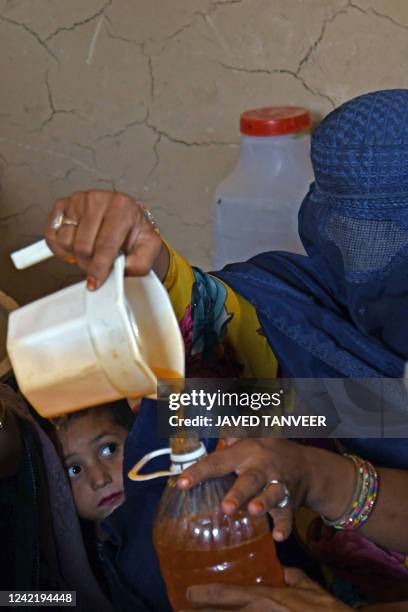 An Afghan burqa-clad woman fills the bottle at a shampoo and soap factory in Kandahar on July 30, 2022.