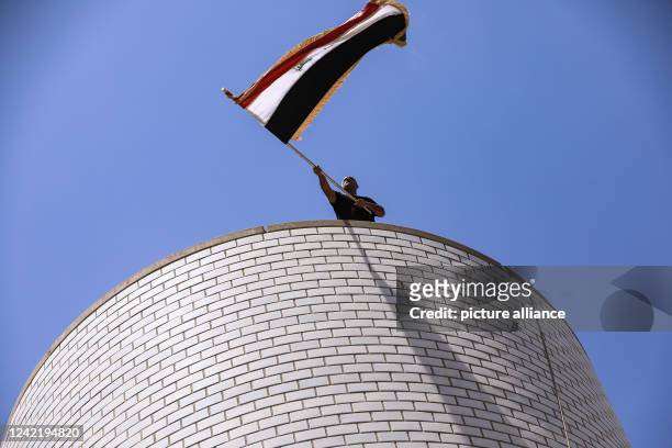 July 2022, Iraq, Baghdad: A man waves the Iraqi flag as supporters of Iraq's influential Shiite cleric Moqtada al-Sadr storm into the Green Zone to...